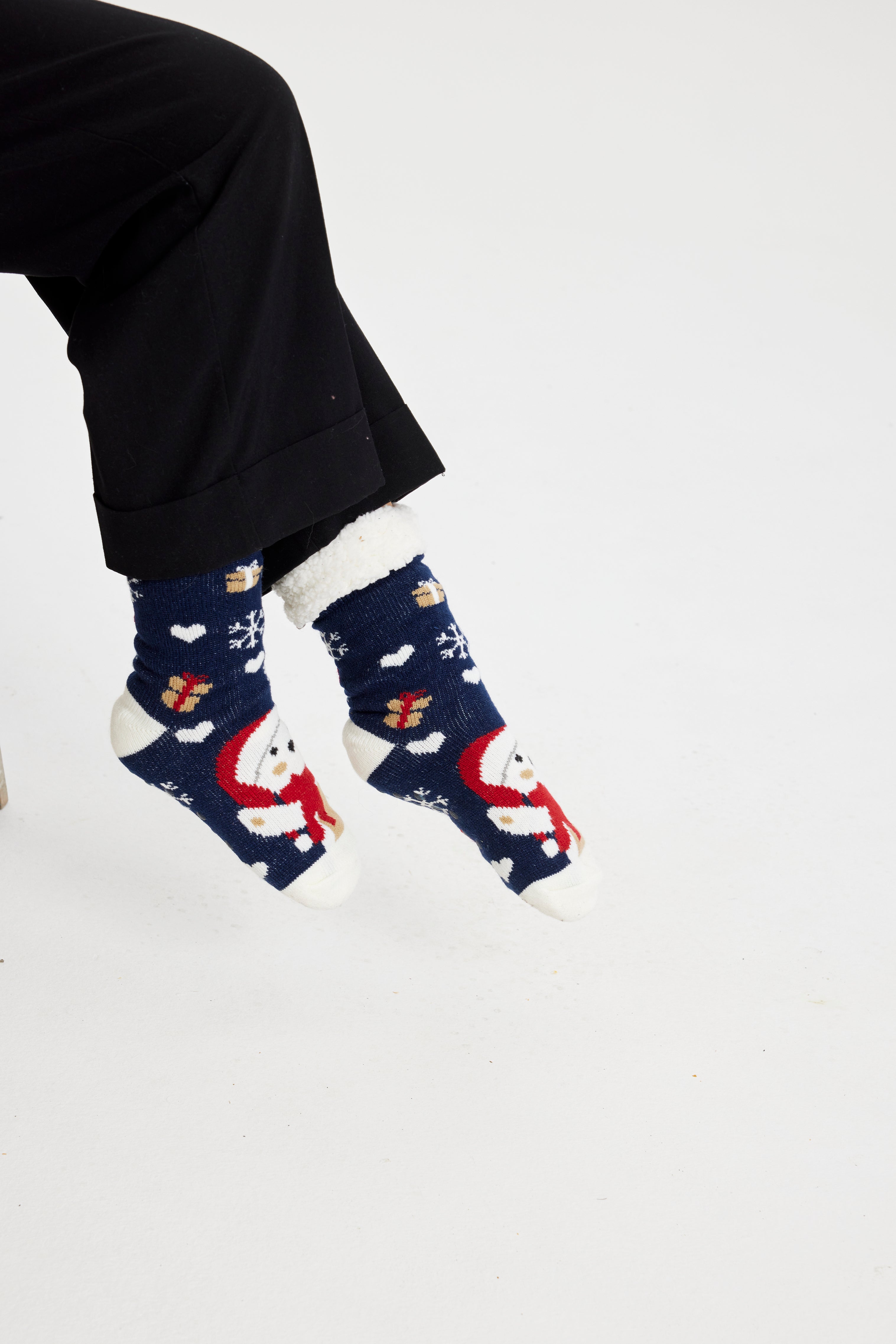 Ett par fötter i blå julstrumpor med jultomten och julklappar på.